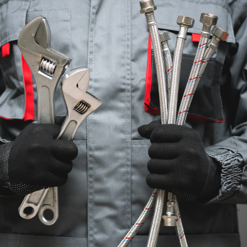 A plumber holding hand tools and supplies.